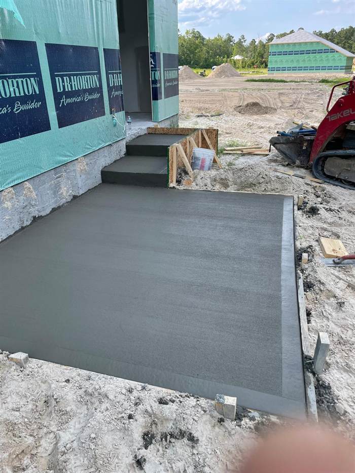 Freshly finished rear concrete patio with formed steps at a house under construction