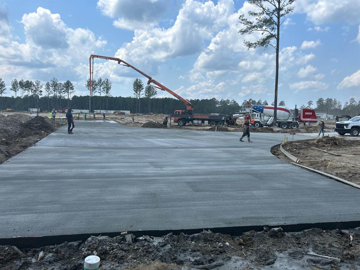 Large commercial concrete pad being placed with a boom pump and a ready-mix truck on site