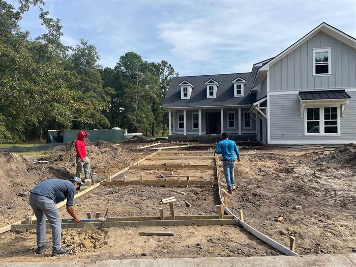 Crew setting and staking timber forms for a new concrete driveway at a farmhouse style home