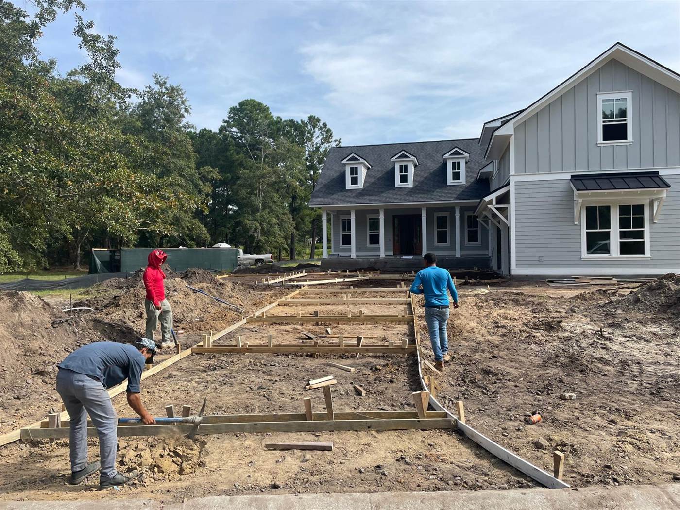 Crew setting and staking timber forms for a new concrete driveway at a farmhouse style home