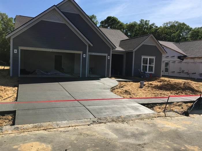 New concrete driveway with a curved edge and sidewalk apron freshly finished at a new home