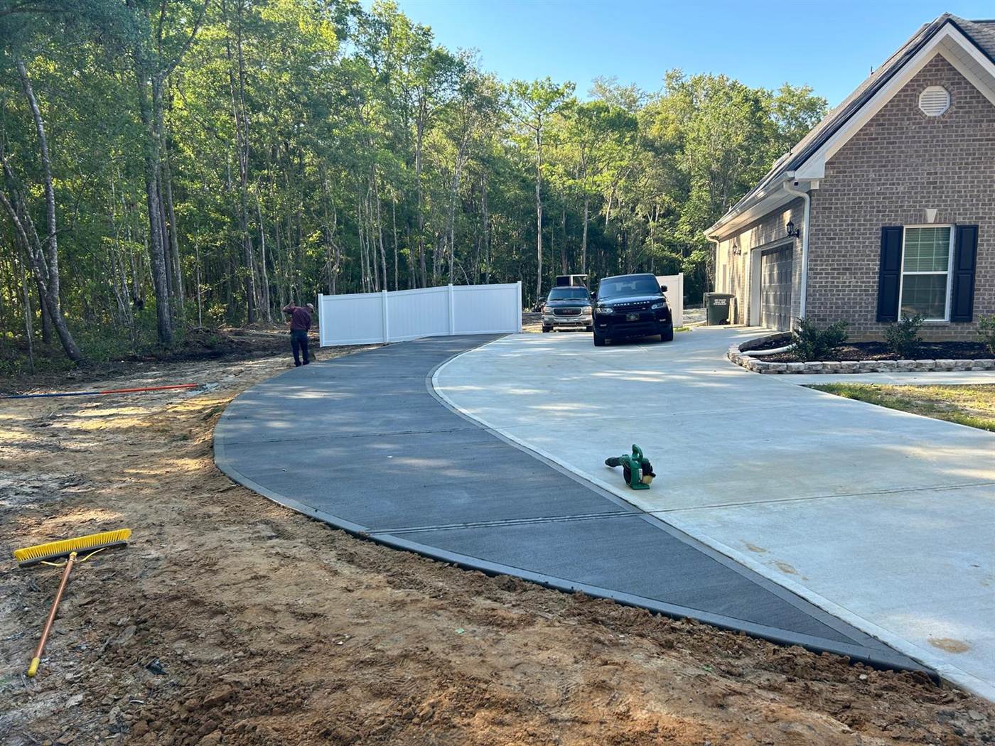 Finished curved concrete driveway with a broom finish leading to the garage of a brick home