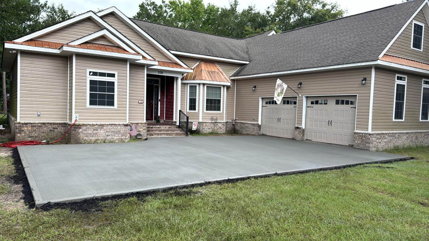 Wide finished concrete driveway and parking apron in front of a two-car garage on a craftsman style home