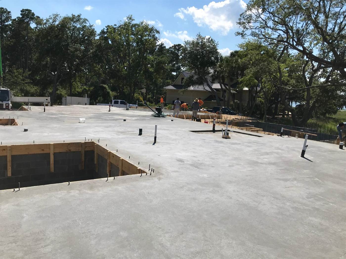 Elevated concrete slab being power trowelled on a block stem wall at a marsh-front Lowcountry lot