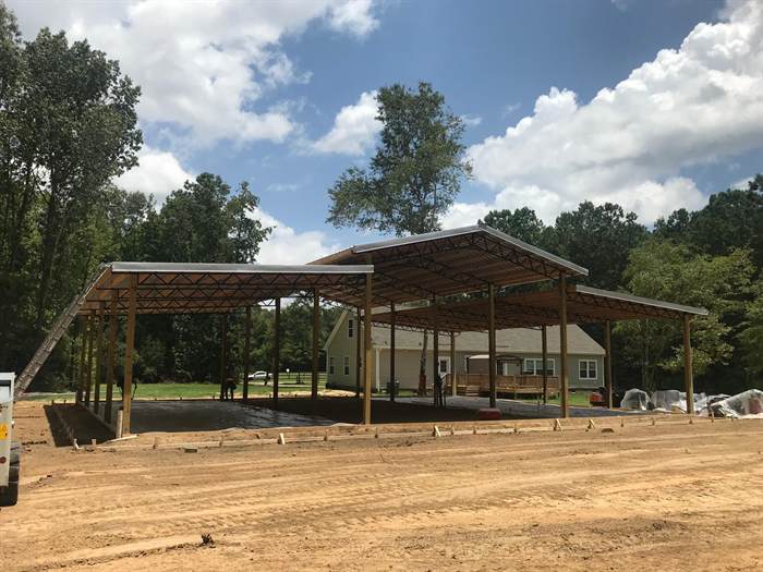 Open pole barn structure erected over a graded pad before the concrete floor is poured