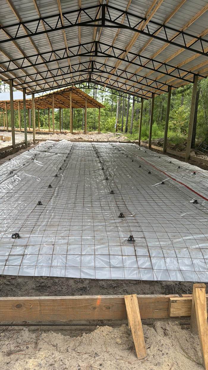 Reinforcing mesh on chairs over a vapor barrier inside a finished pole barn ready for the floor pour