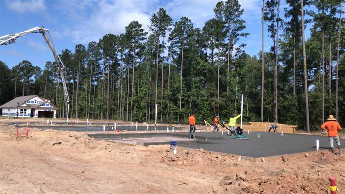 Power trowel finishing a freshly poured house slab with the formed perimeter visible