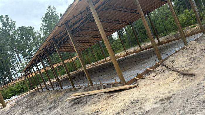 Vapor barrier and perimeter forms in place under a pole barn frame ahead of a concrete floor pour