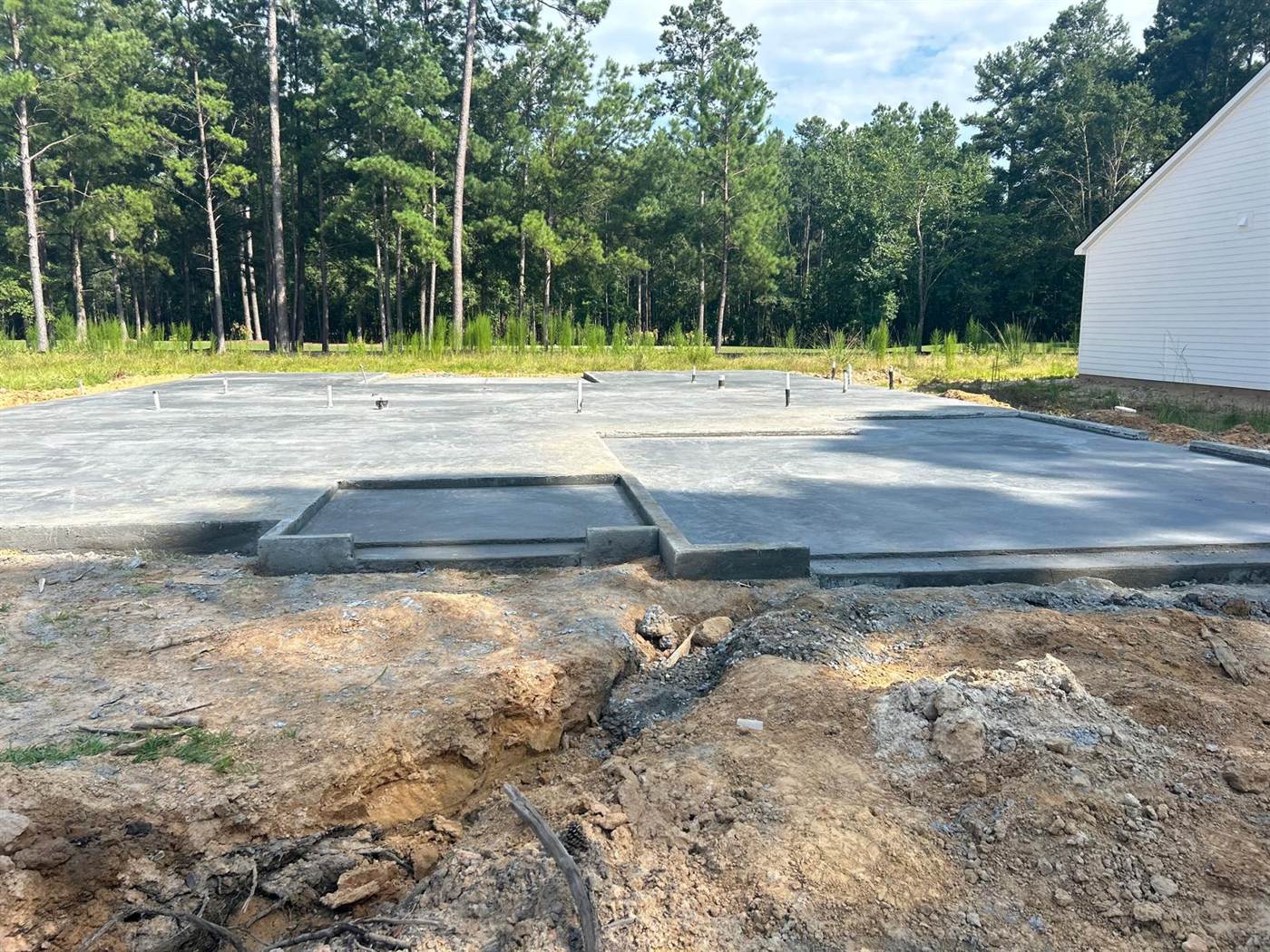 Finished house slab with a separate lowered porch slab and plumbing stub-ups awaiting framing