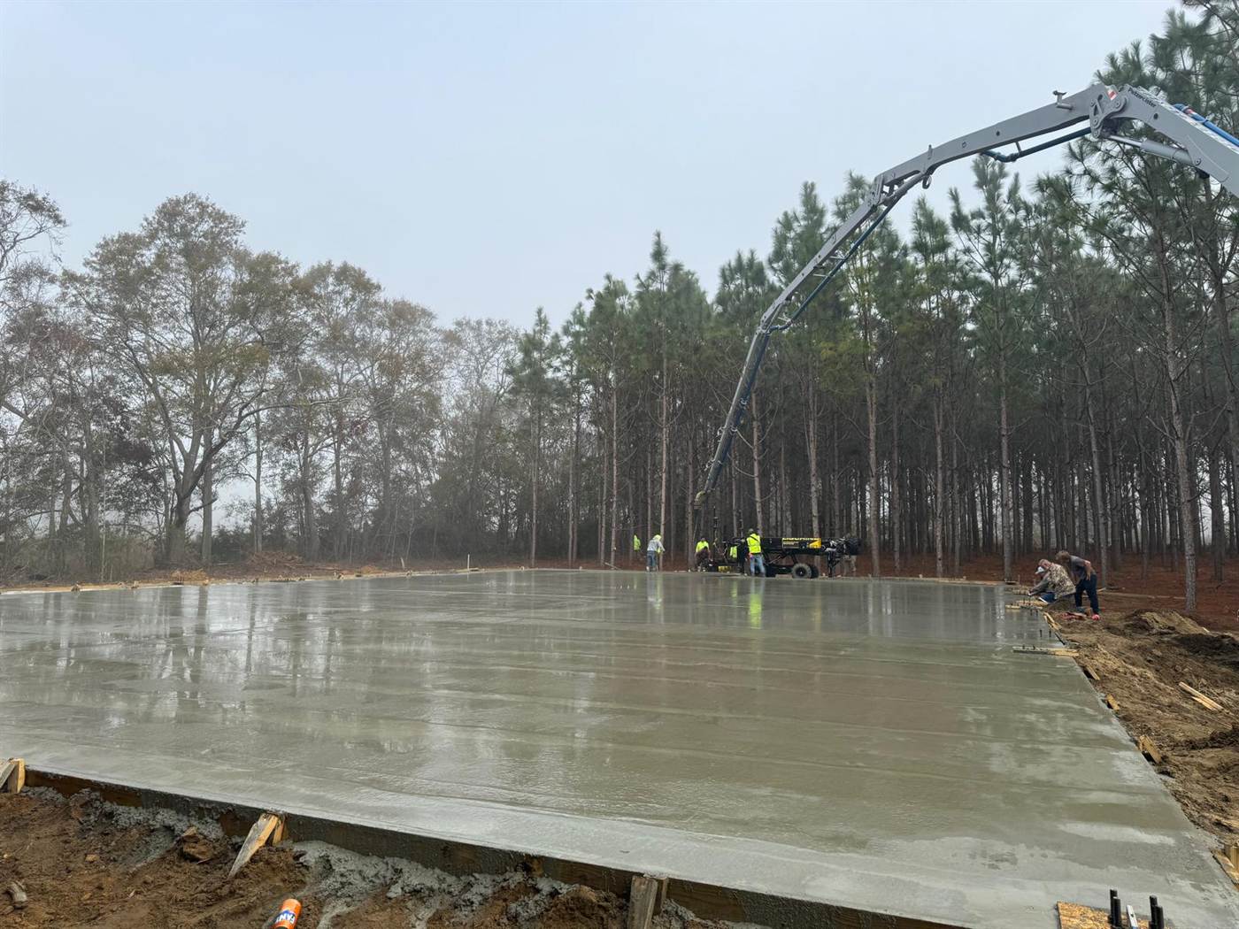 Large concrete slab finished on a foggy Lowcountry morning with a boom pump still extended over the pour
