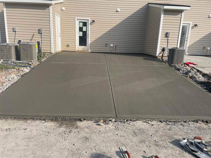 Finished concrete patios and equipment pads along the rear of new townhomes